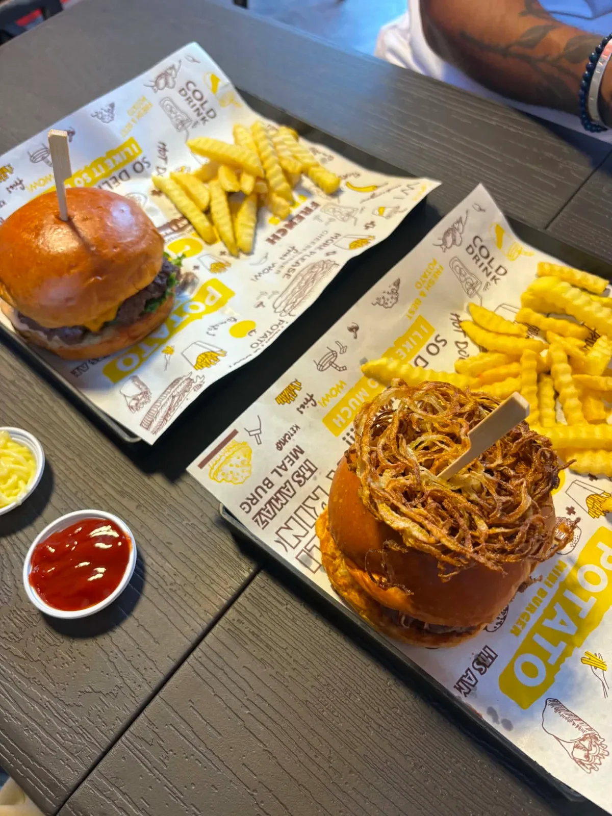 เบอร์เกอร์สองชุดพร้อมเฟรนฟรายและซอสมะเขือเทศบนโต๊ะร้าน